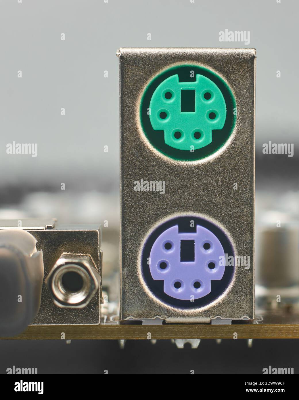 silver metallic ps2 housing on motherboard, green and purple plastic ports for mouse and keyboard, closeup with soft focus, legacy computer hardware Stock Photo