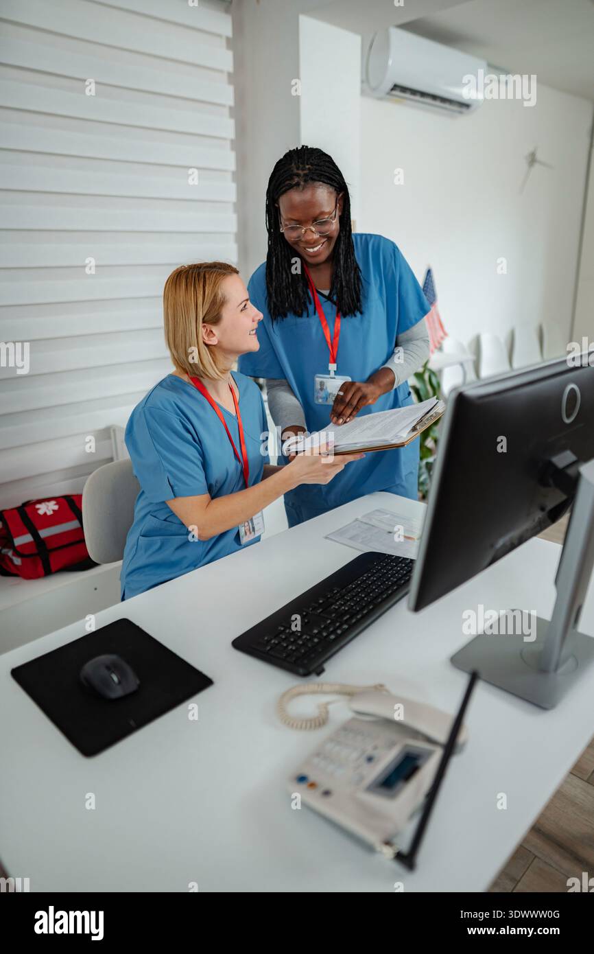 Two nurses collaborating on patient care at a reception desk Stock Photo