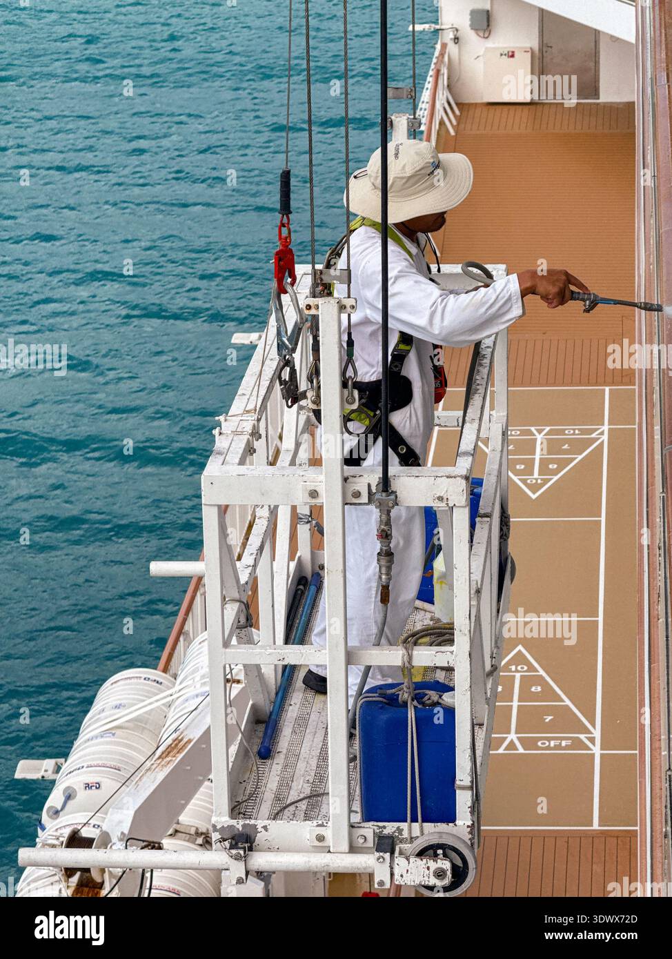 Tortola, British Virgin Islands - 18 January 2026: Member of crew of a cruise ship on a cradle platform using a pressure washer to clean windows - Smartphone Captured Stock Image