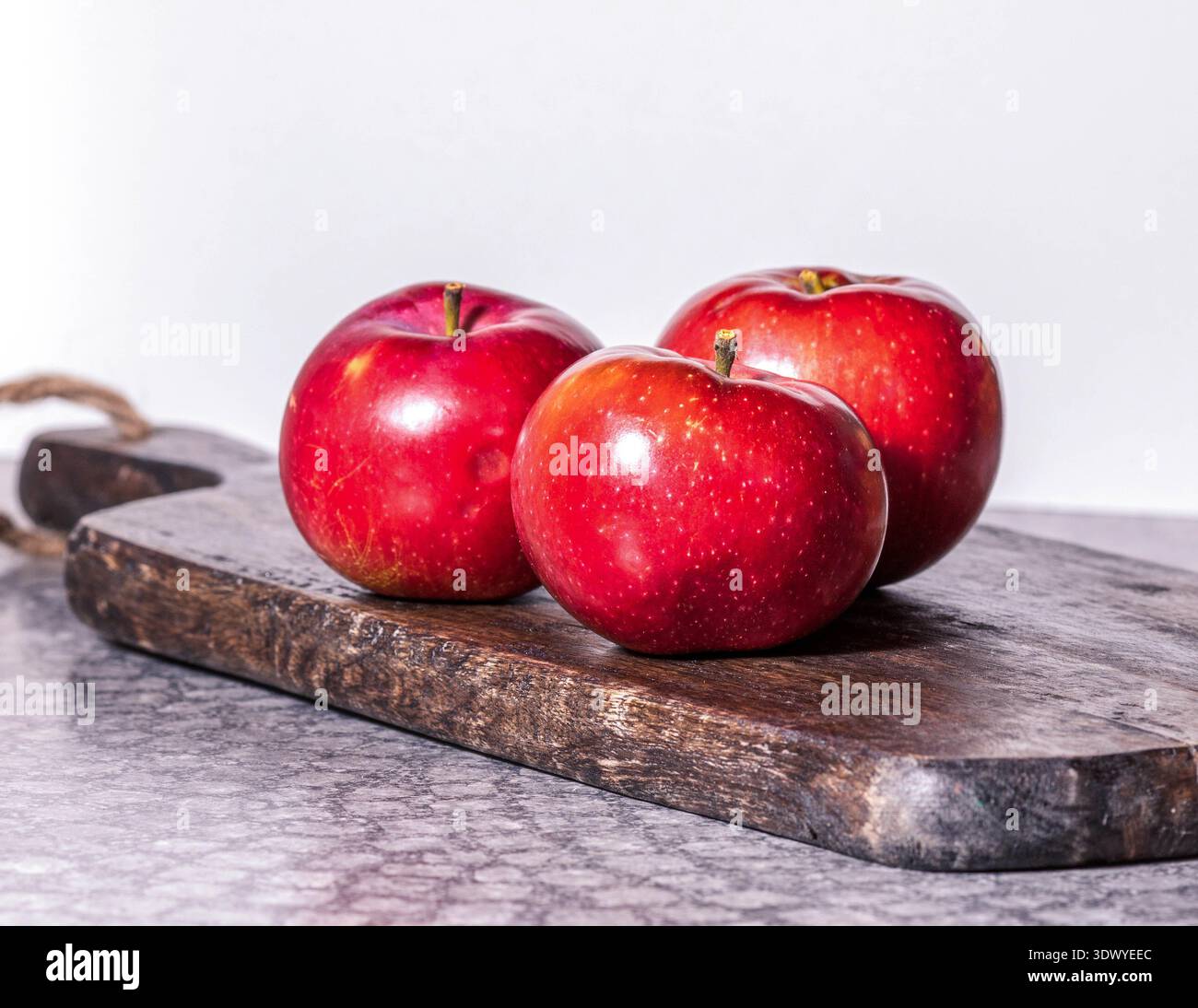 Fresh red apples on rustic wooden cutting board. Stock Photo