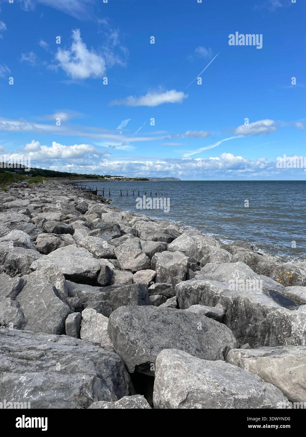 Rocky coastal shoreline under bright blue sky, North Wales coast, United Kingdom - Smartphone Captured Stock Image