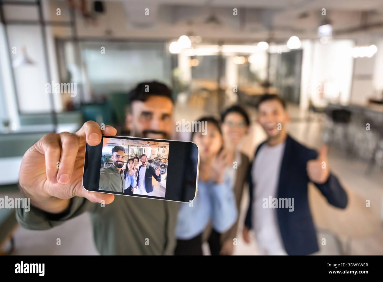 Diverse business team displayed on smartphone screen while taking selfie Stock Photo