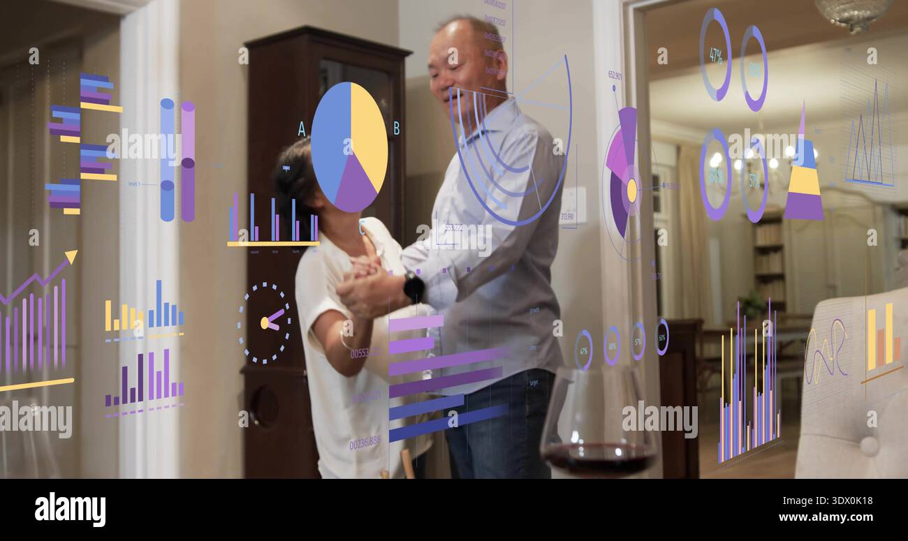 Dancing mature couple holding hands in living room, wearing casual clothes with AR charts Stock Photo