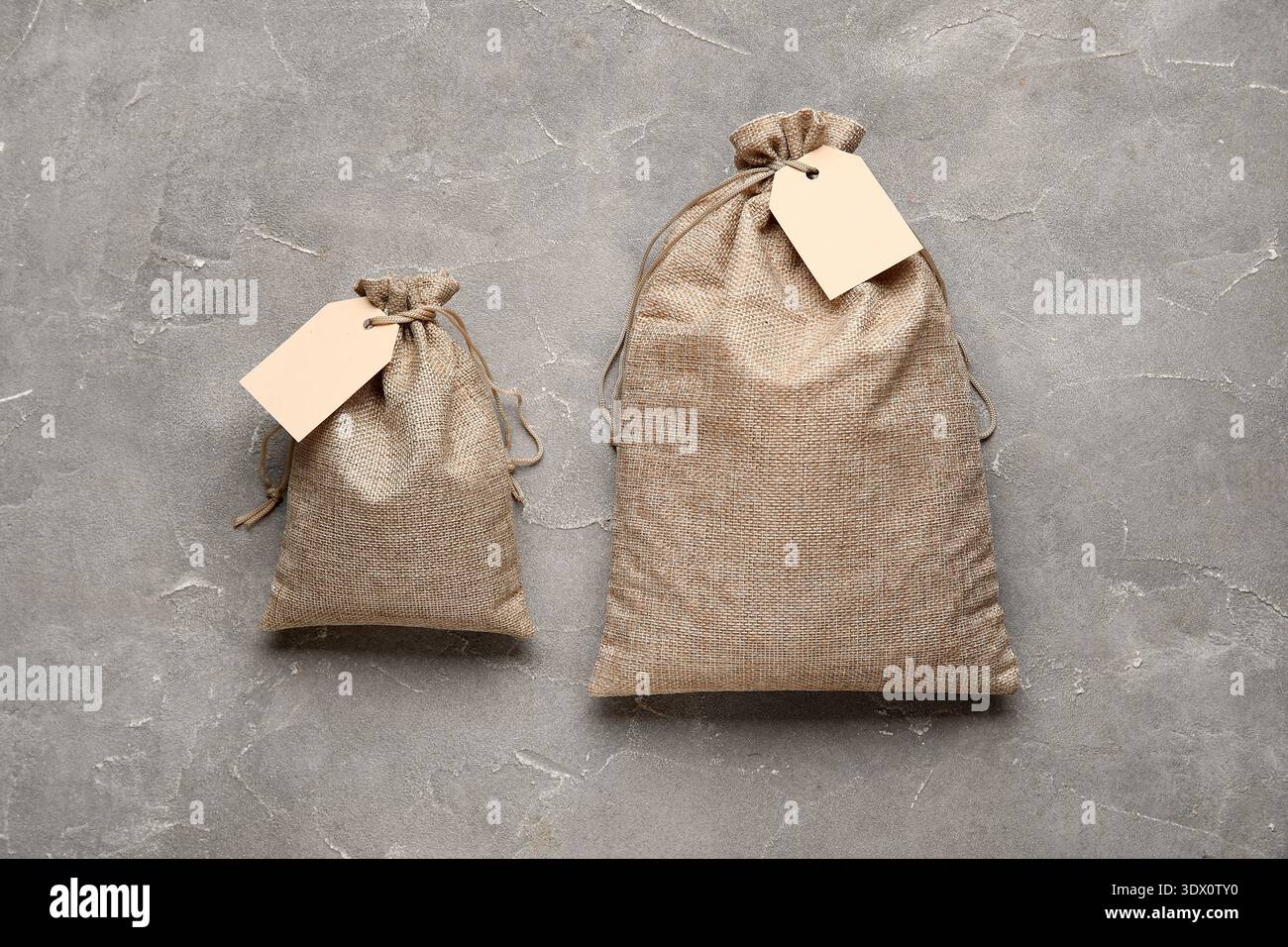 Full sacks with tags on grunge grey background Stock Photo