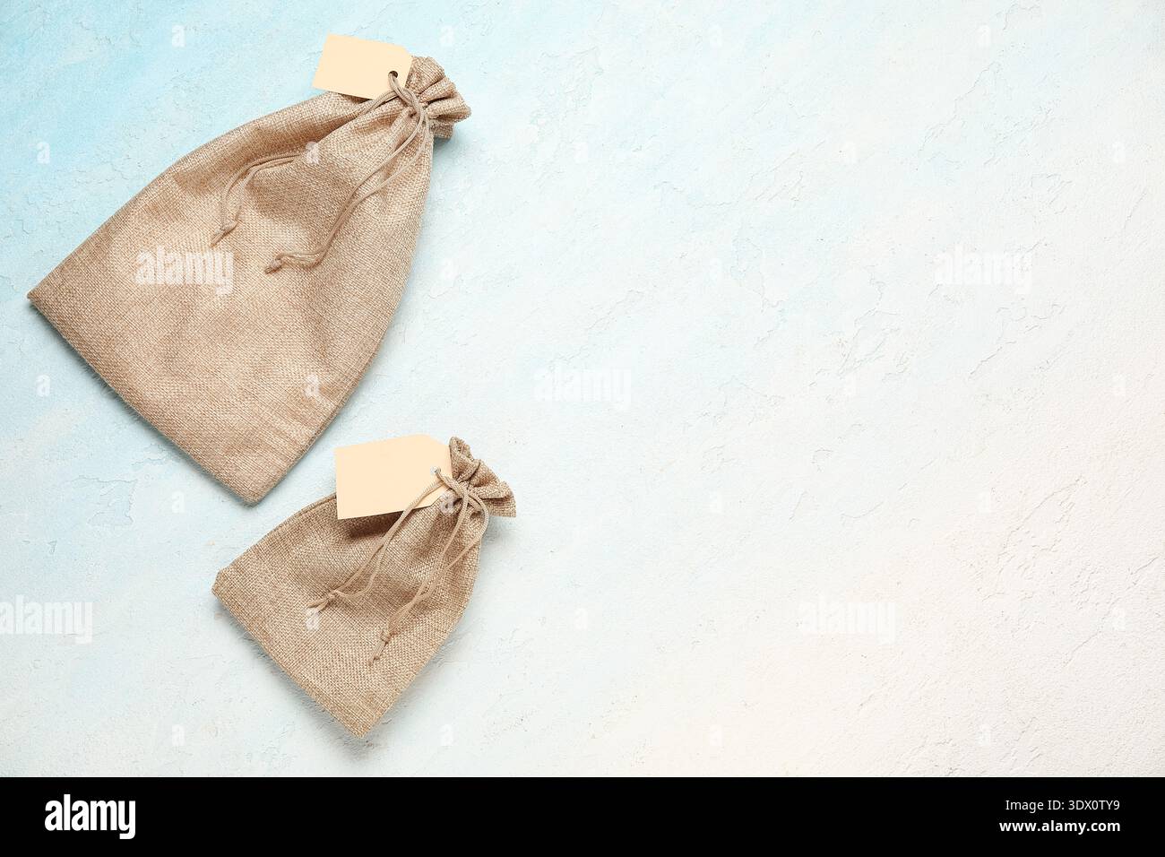 Empty sacks with tags on color background Stock Photo