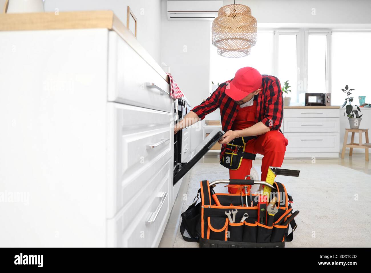 Male technician checking oven in kitchen Stock Photo