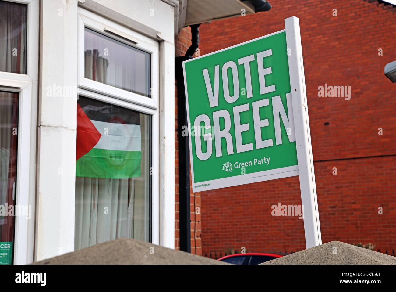 Vote Green sign and Palestinian flag in a window in Levenshulme, Manchester, England, highlighting local campaigning and Gaza solidarity themes. Stock Photo