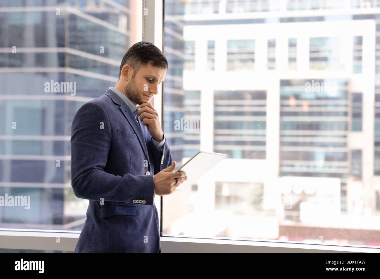 Focused businessman thoughtfully analyzing data or read information on tablet Stock Photo