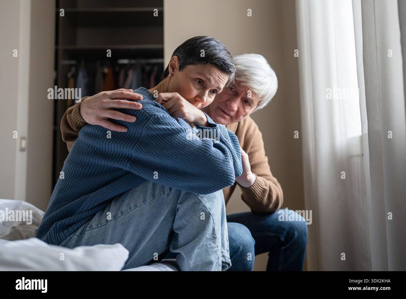 Manipulative abusive husband trying to make peace with depressed apathetic wife after conflict. Stock Photo