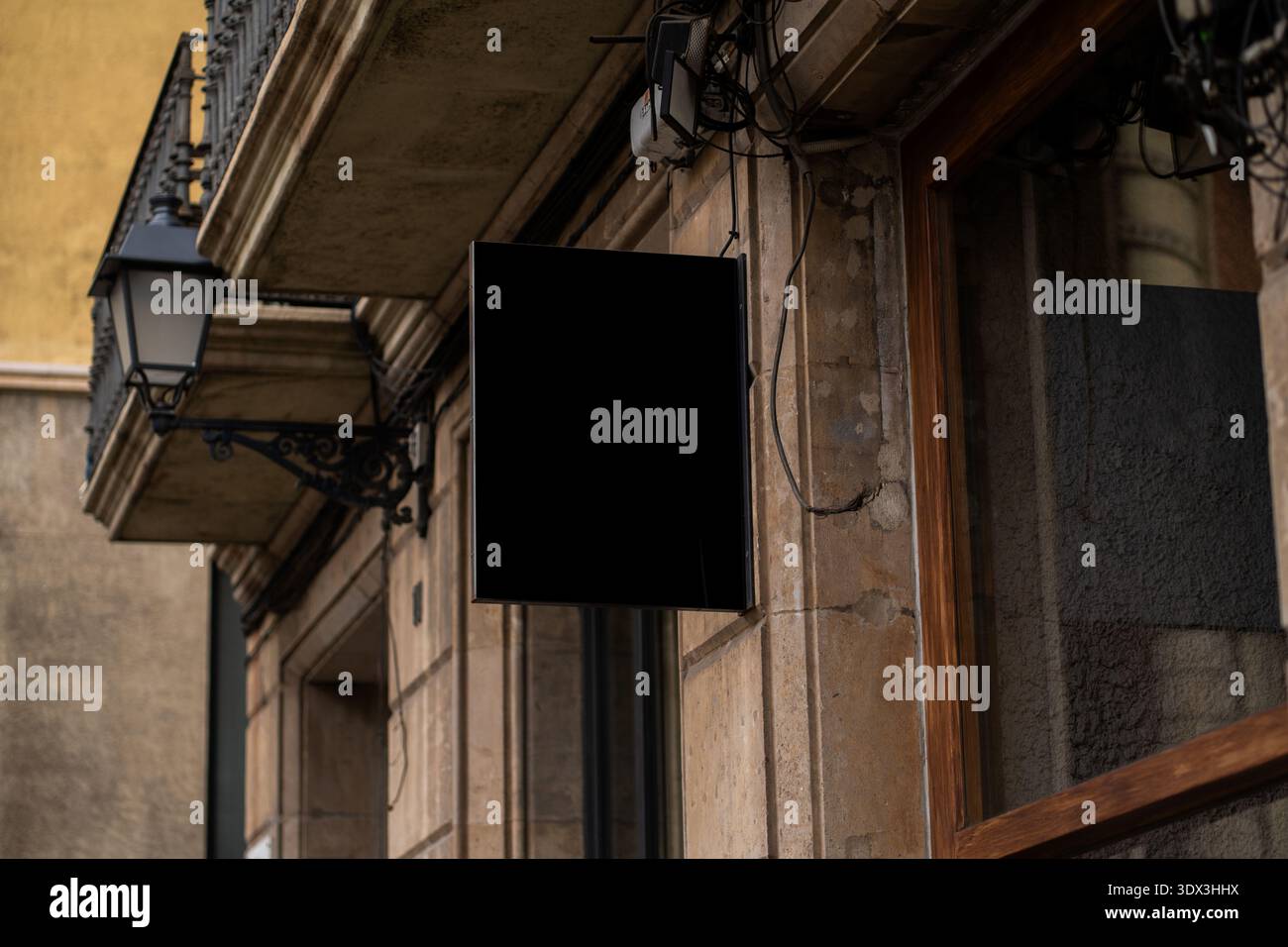 Blank black rectangular storefront sign mockup hanging on old stone building Stock Photo