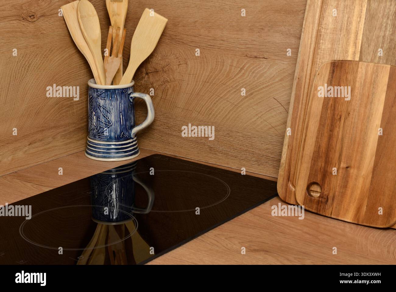 Wooden kitchen utensils and hotplate cooktop hob in modern apartment, home cooking concept Stock Photo