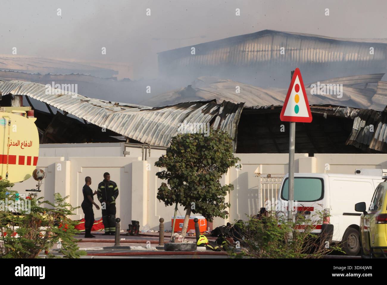 Firefighters work as smoke rises outside a damaged warehouse in an ...