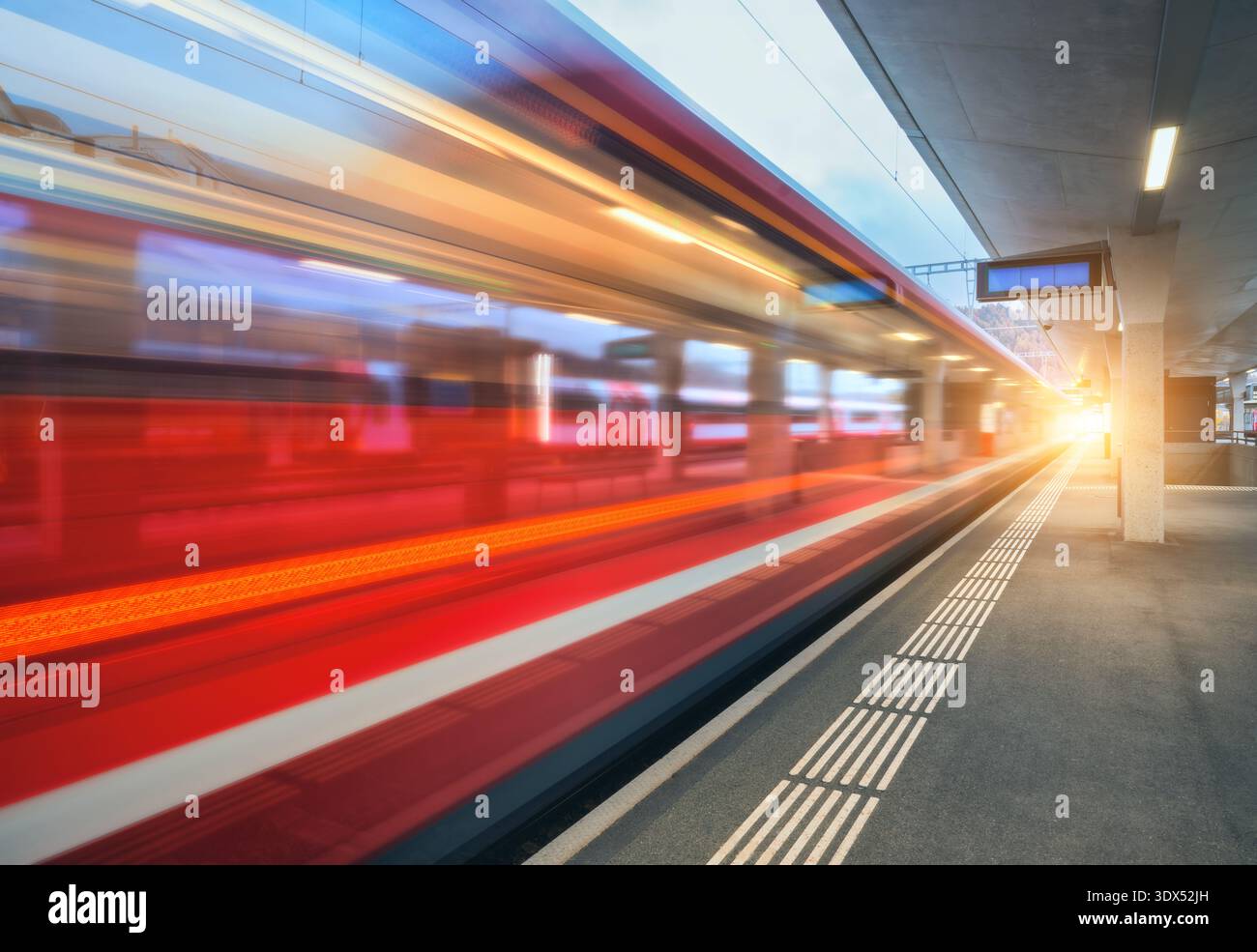 Blurred red passenger train passing mountain railway station Stock Photo