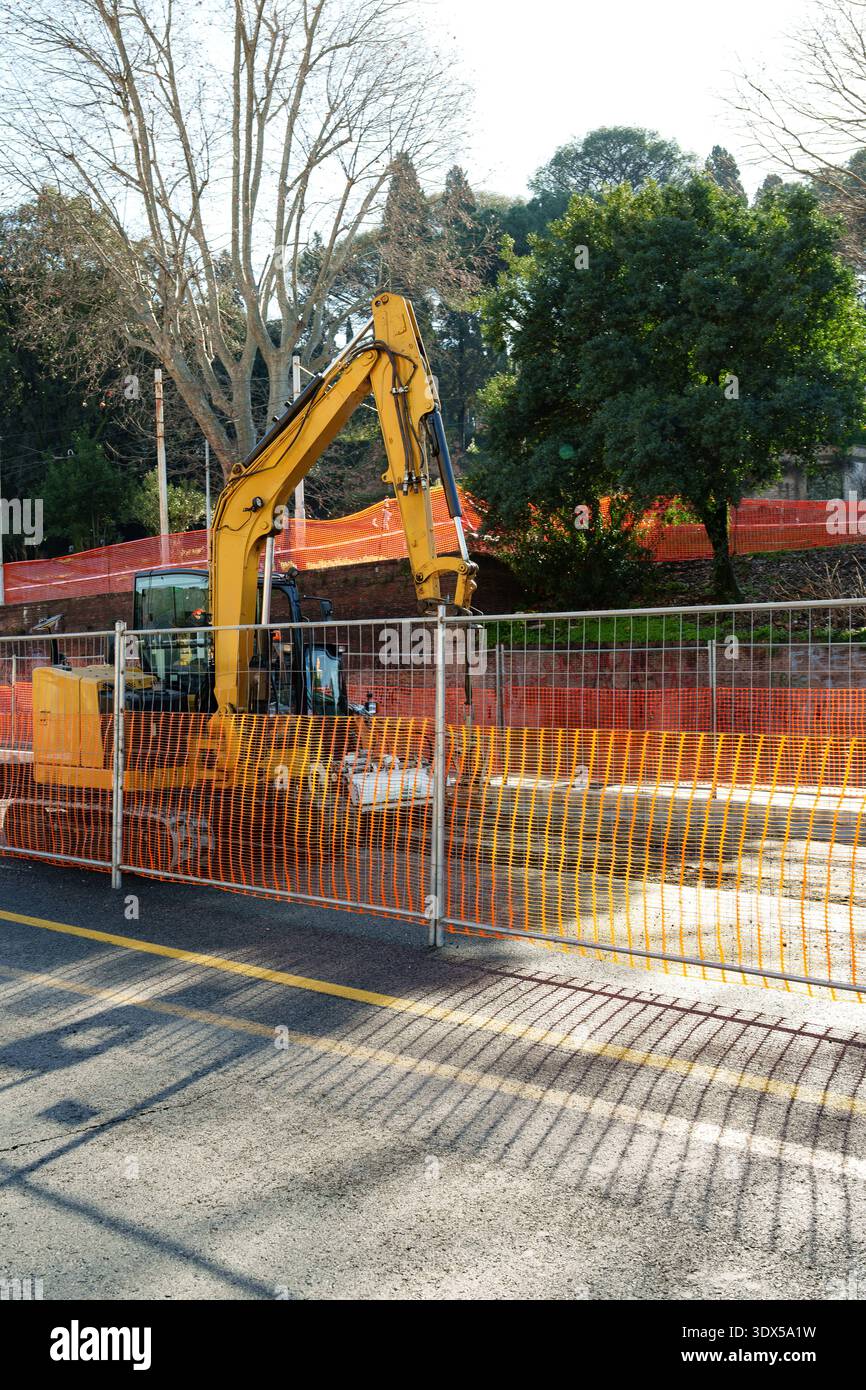 Construction work takes place in a city area with a large yellow ...
