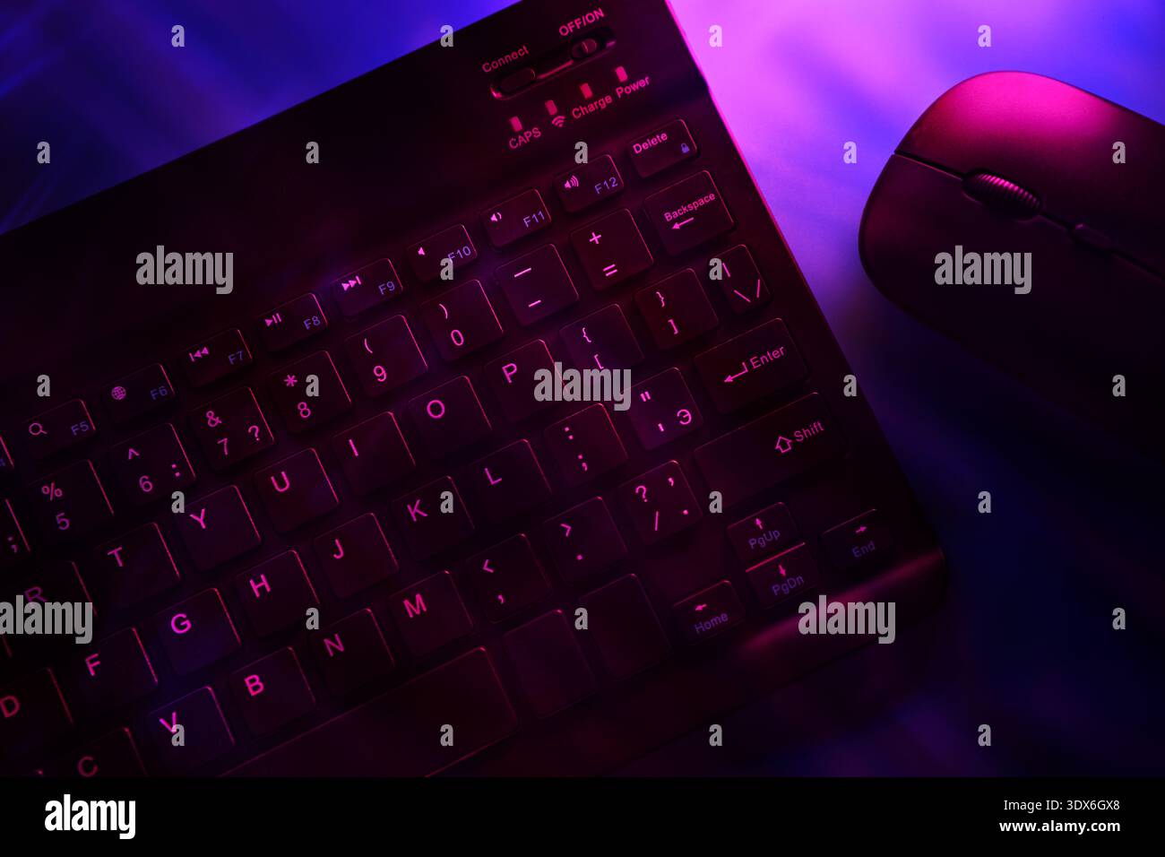 Close-up of a keyboard and mouse, with vibrant purple light highlighting just part of the mouse, creating a modern, tech-savvy vibe perfect for AI and Stock Photo