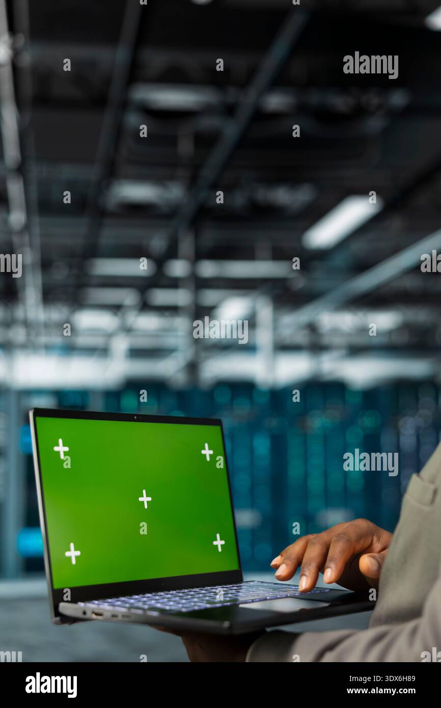 Close up of technician using green screen laptop in data center, managing rackmounts systems. Server hub employee using mockup notebook, installing upgraded infrastructure Stock Photo