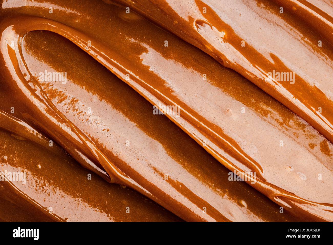 A close-up image of rich, smooth salted caramel showcases its glossy, creamy texture. The caramel's warm, inviting tones highlight its delicious appea Stock Photo