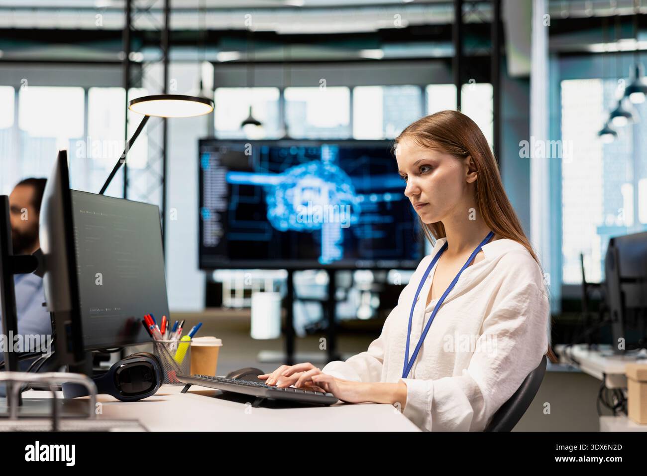 Junior dev in tech startup utilizing AI to optimize performance and forecast issues. Young female engineer writing code in office, training machine learning models using PC Stock Photo