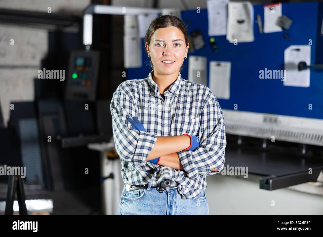 Smiling young female worker posing in metalworking workshop Stock Photo
