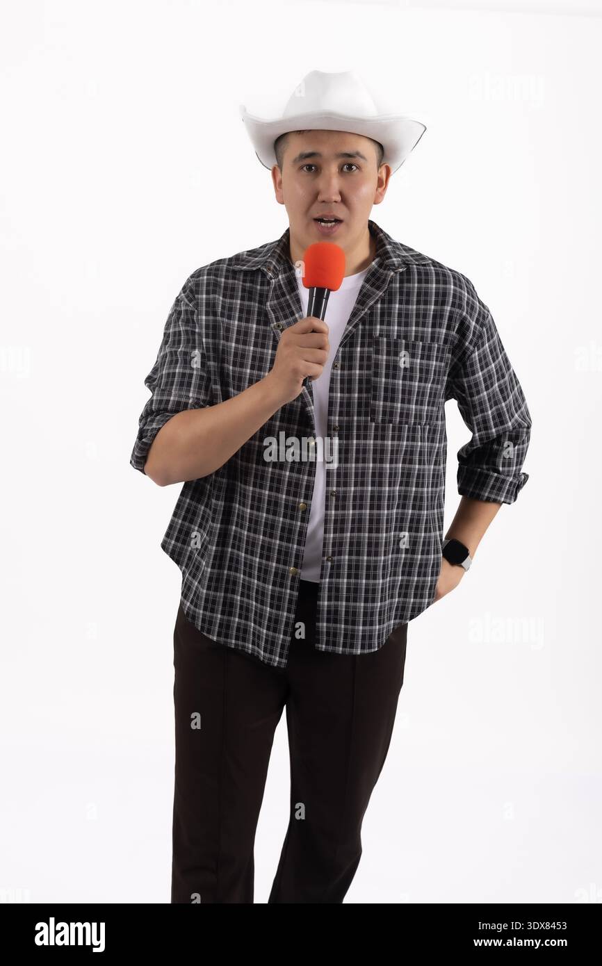 Confident male singer holding microphone and posing in studio Stock Photo