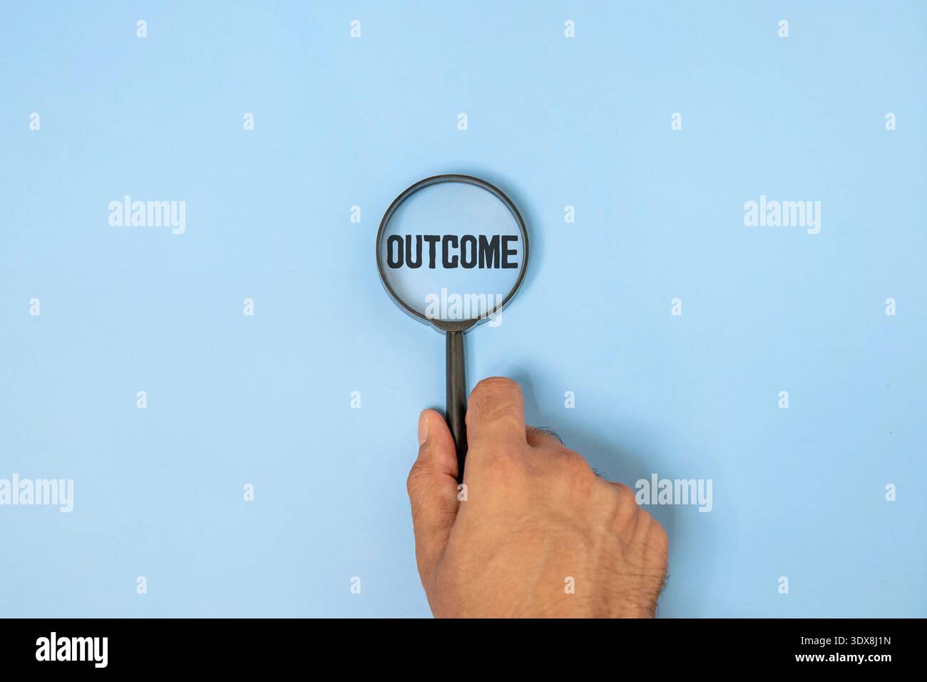 A hand holds a magnifying glass over the word OUTCOME on a blue background. Business goals, performance focus, strategic results, and data analysis Stock Photo