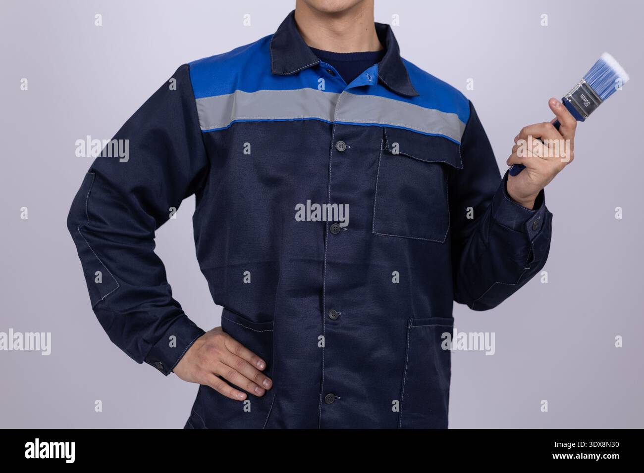 Worker in blue uniform holding a wrench Stock Photo