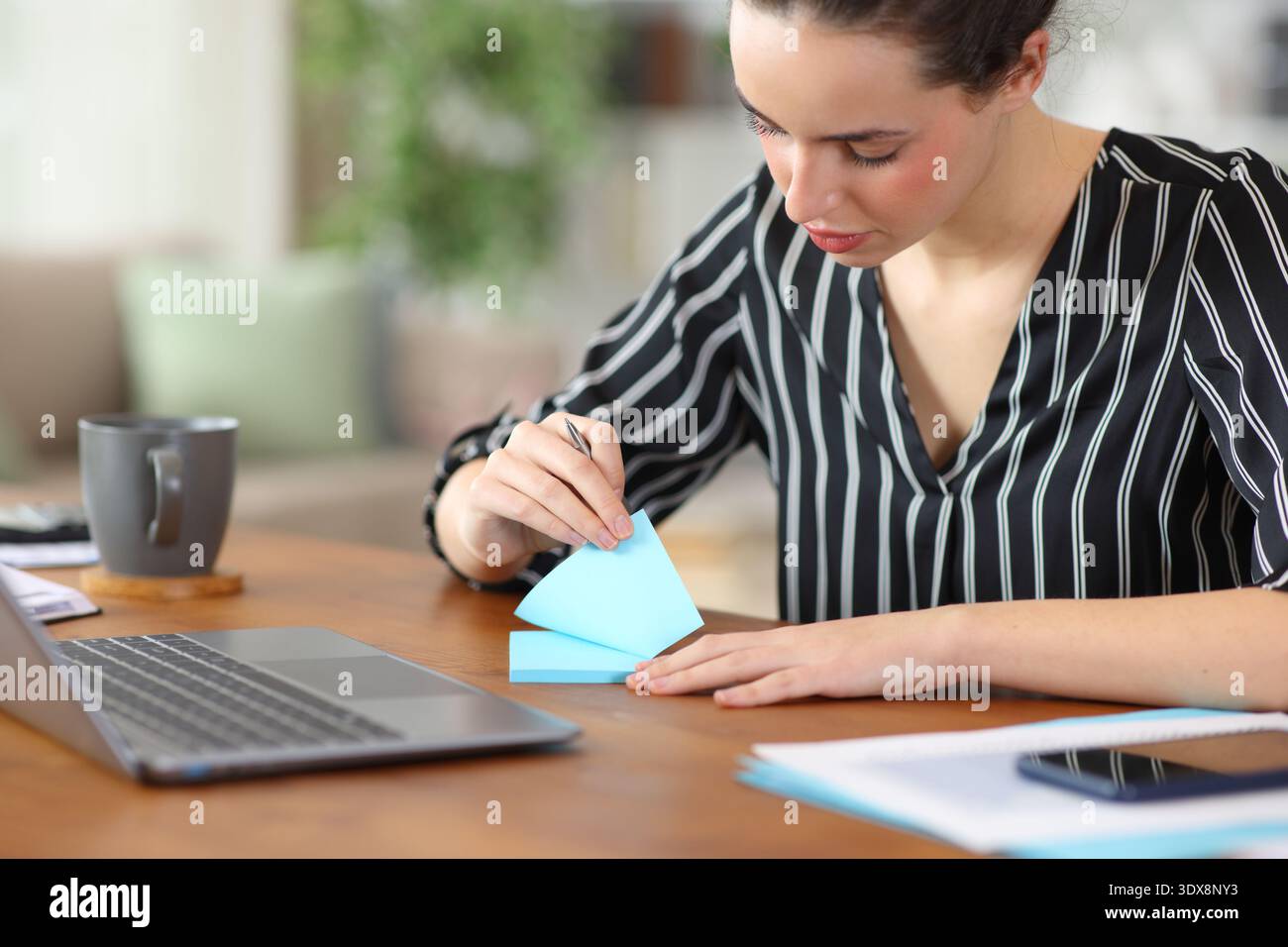 Serious tele worker using blue sticky note working at home Stock Photo