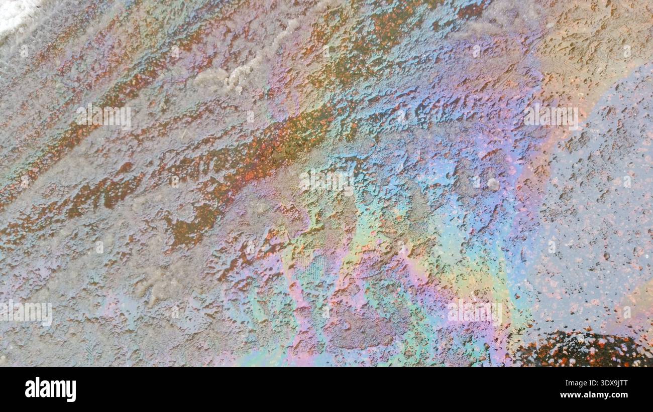 Oil spilled on melting snow. Stock Photo