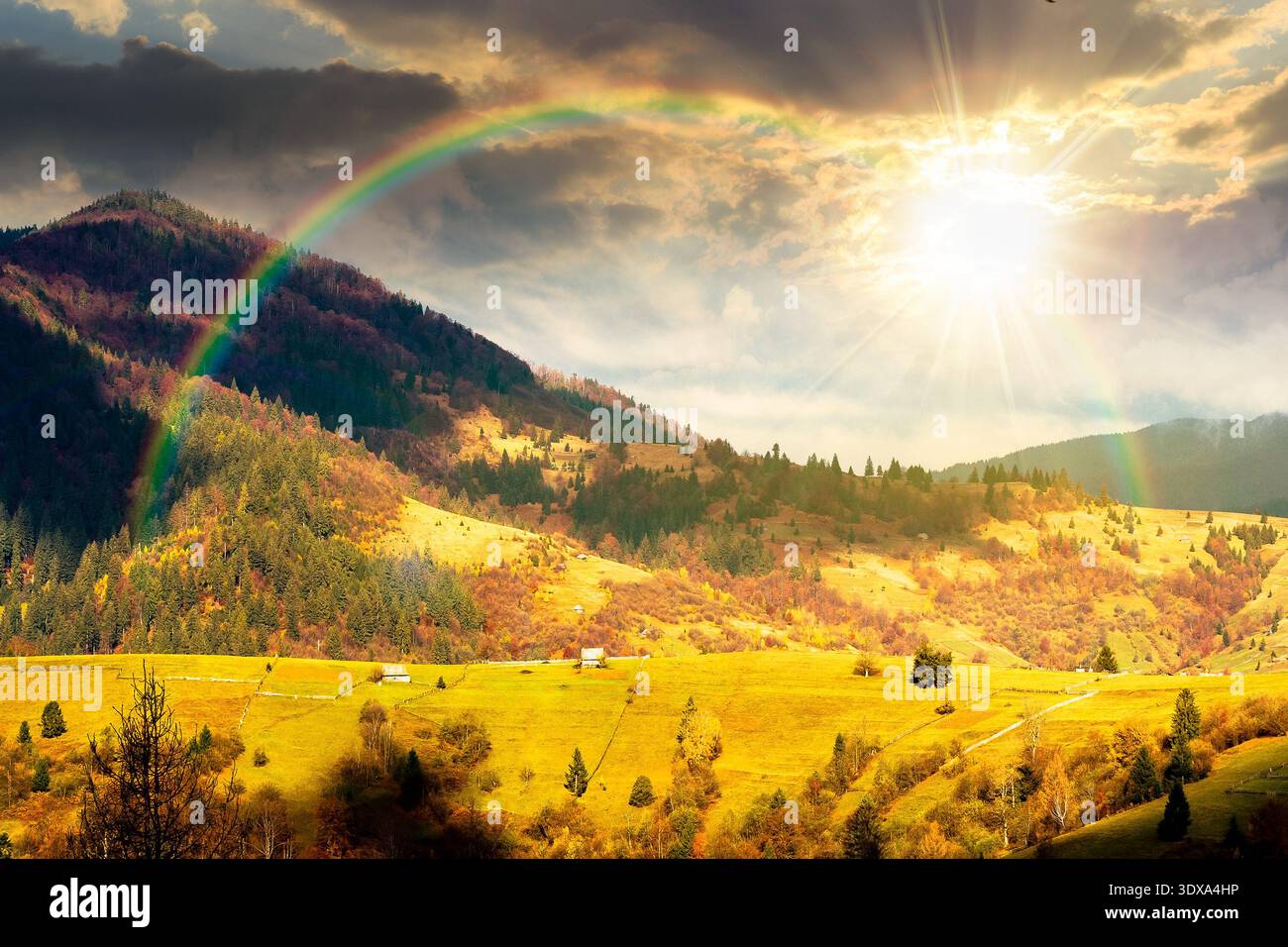 autumn landscape of rural region in mountains at sunset. rolling hills with green alps in dappled evening light. serene countryside under cloudy sky. Stock Photo