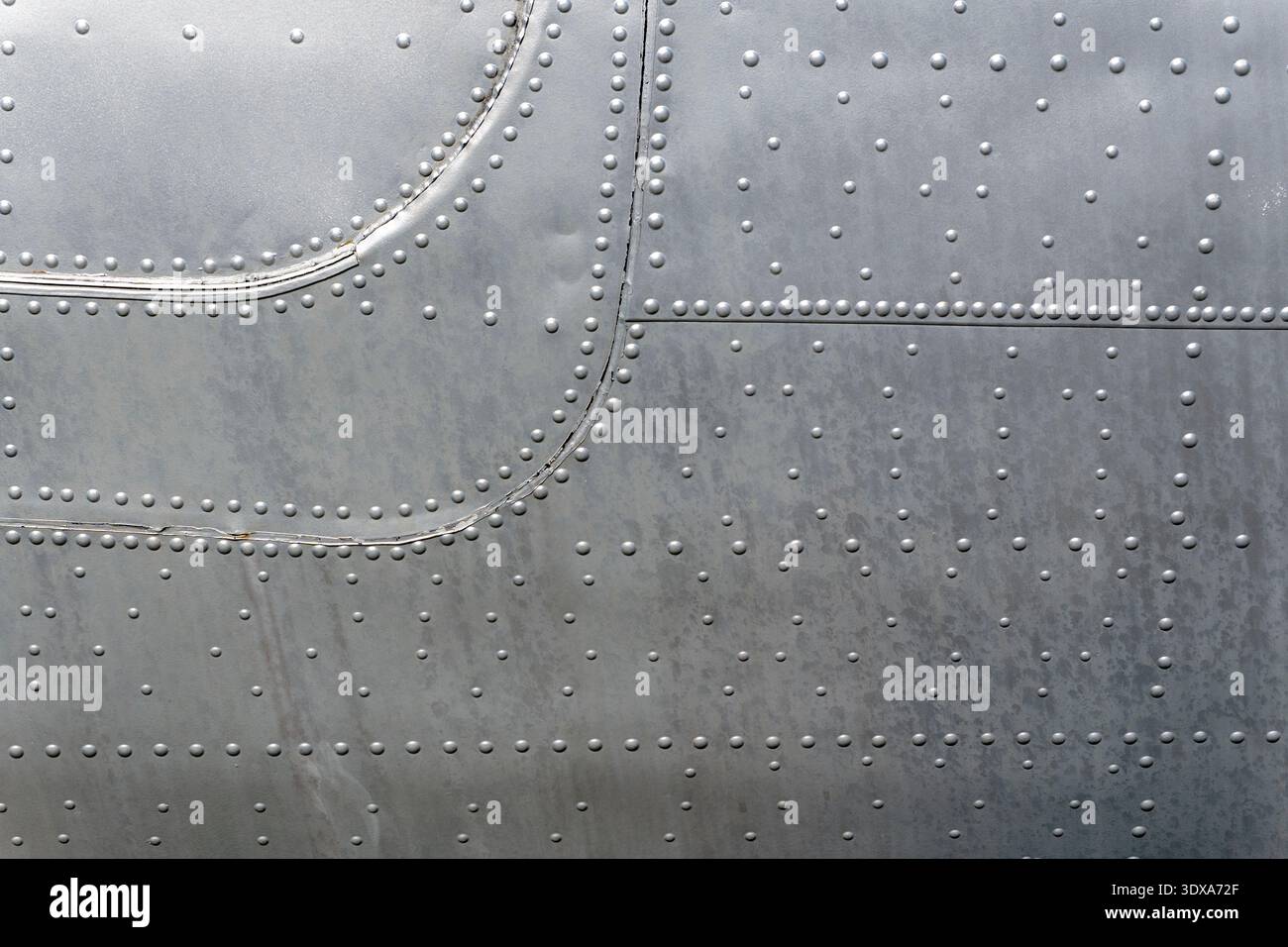 Metal surface of an aircraft displays a shiny texture with many rivets ...