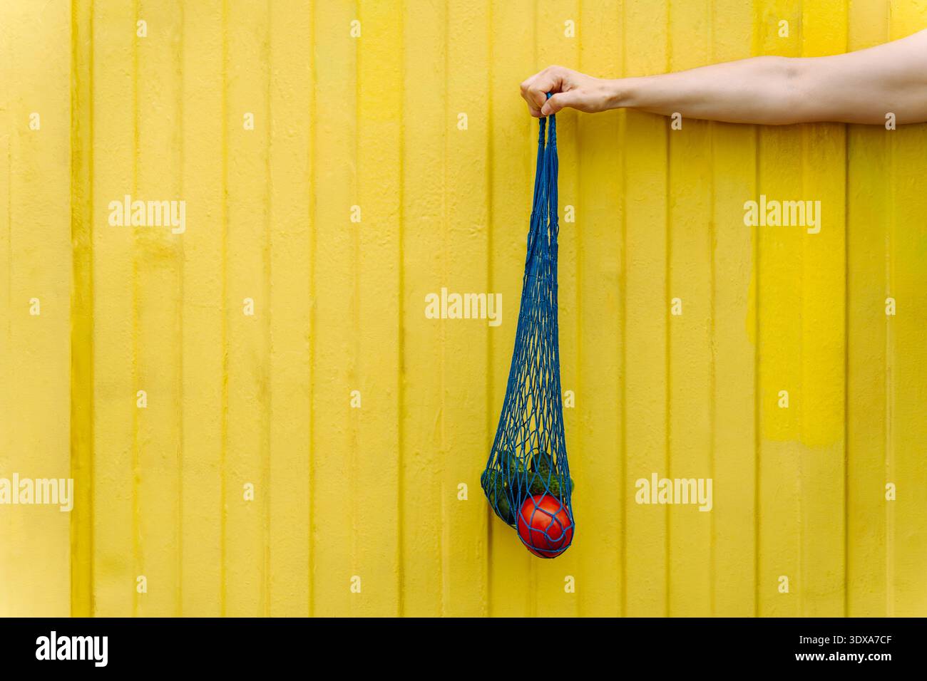 Eco-friendly mesh tote with fresh veggies isolated on yellow background Stock Photo