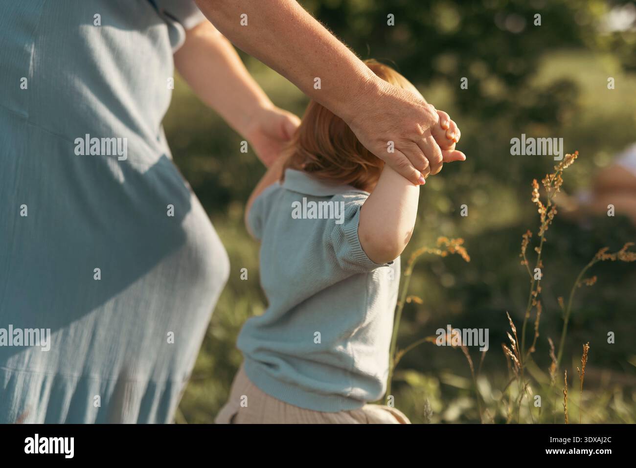 Mother holding hands of son walking in garden Stock Photo
