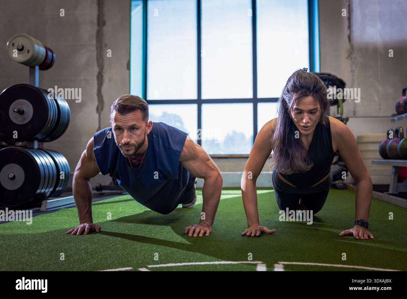 Determined athletes doing push-ups while working out in gym Stock Photo