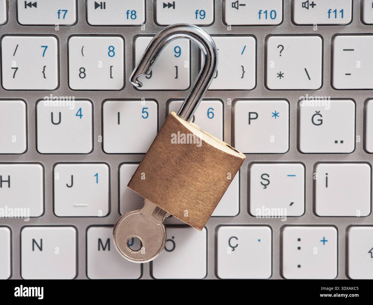 Unlocked padlock with a key resting on a computer keyboard, symbolizing data vulnerability, internet security risks, and privacy threats Stock Photo