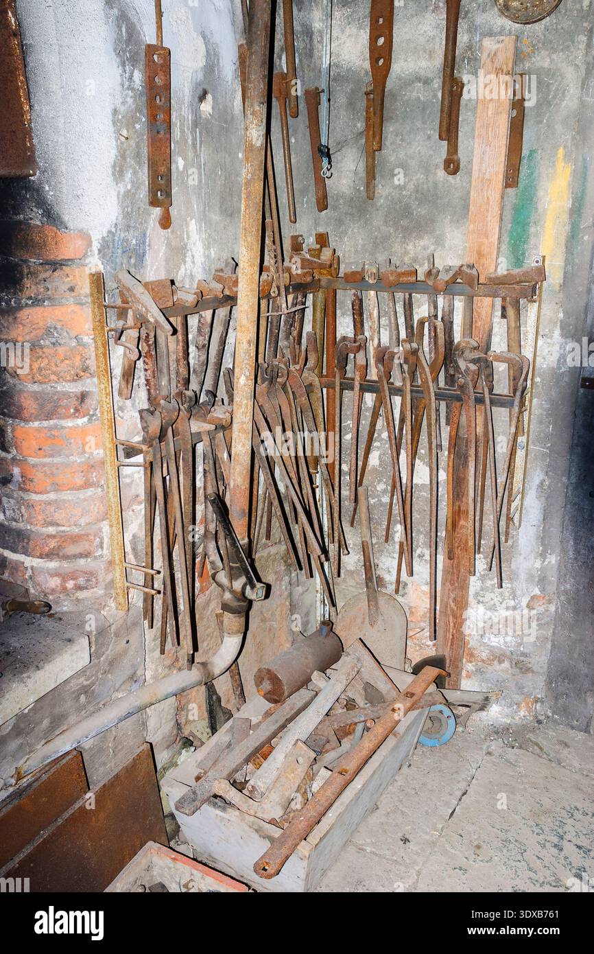 Old forge with tools hanging on a wall Stock Photo