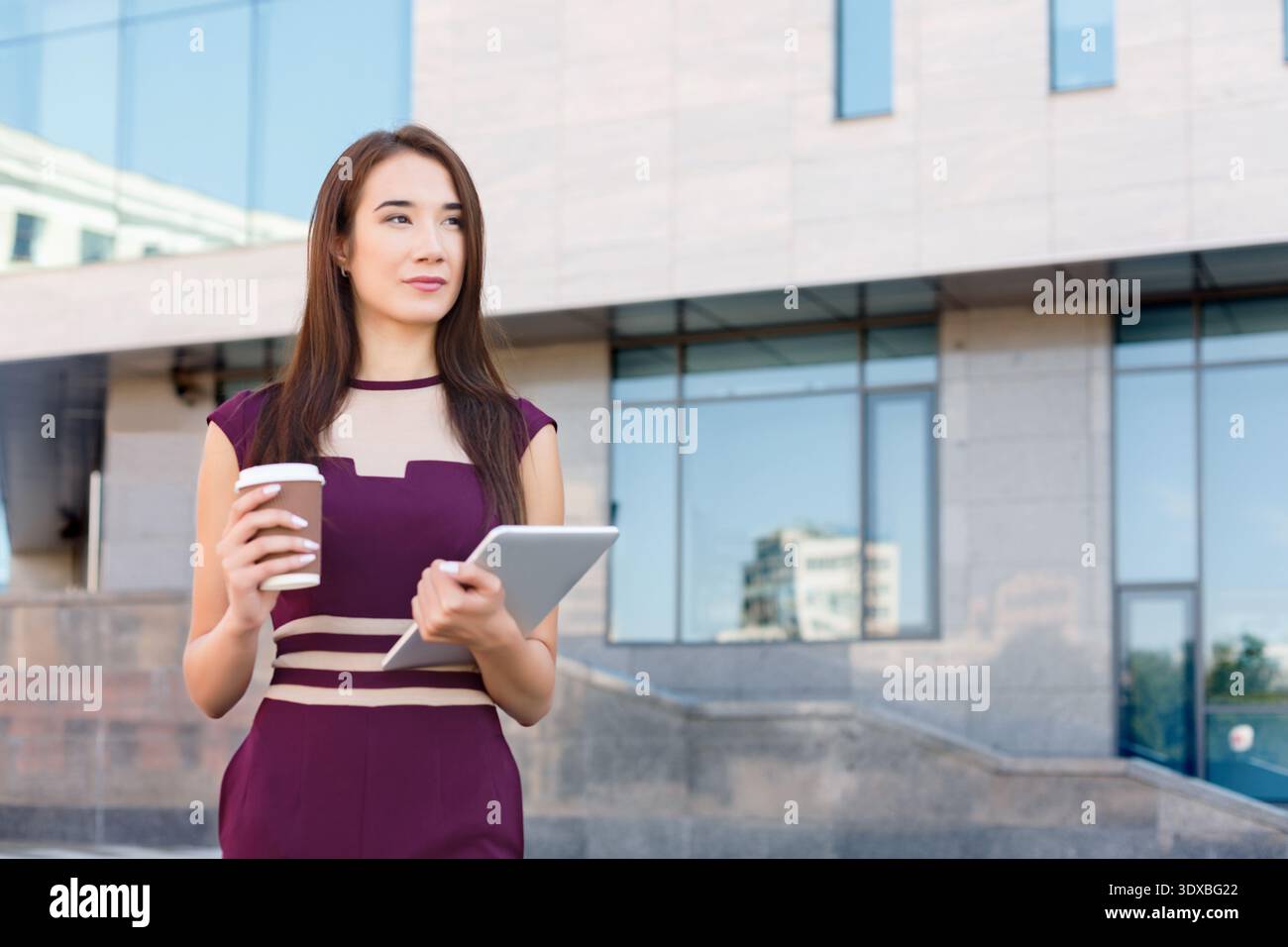 Woman Holding Coffee and Tablet in City Setting During Day Stock Photo