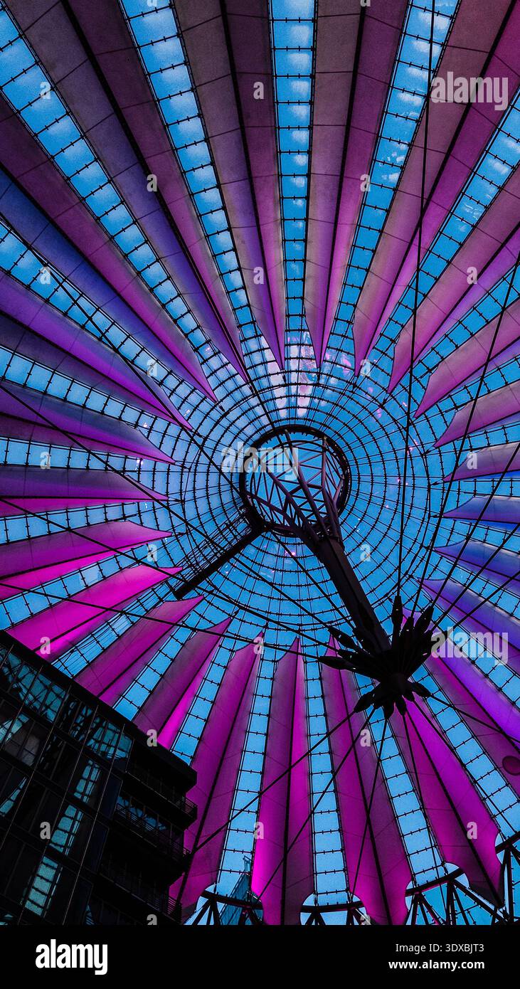 Striking low-angle view of Sony Center’s iconic conical glass roof at Potsdamer Platz in Berlin, radiating panels in vibrant purple and magenta hues a - Smartphone Captured Stock Image