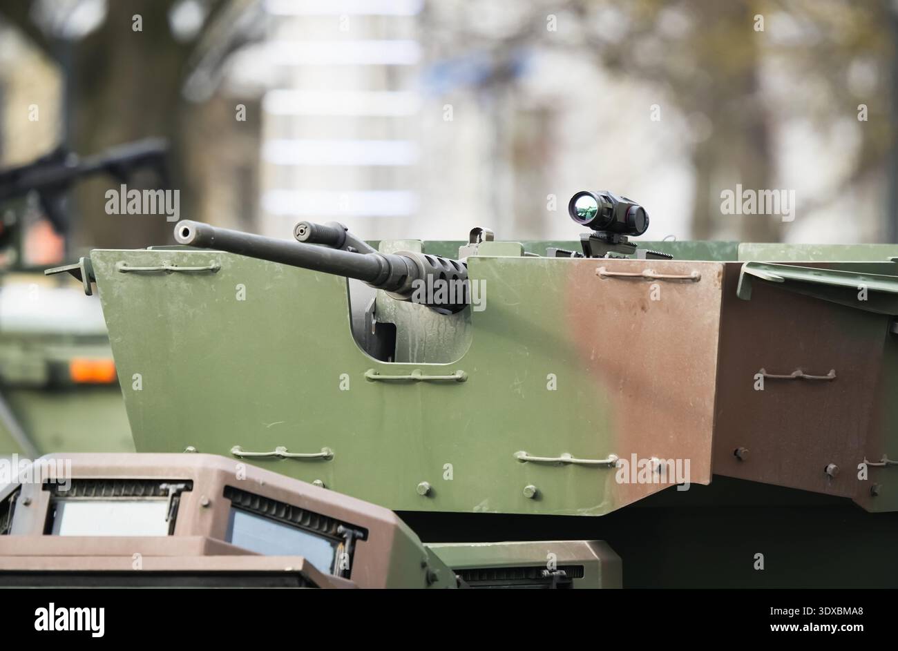 Heavy machine gun mounted on armored vehicle turret featuring advanced thermal imaging scope for precision targeting during military combat operations Stock Photo
