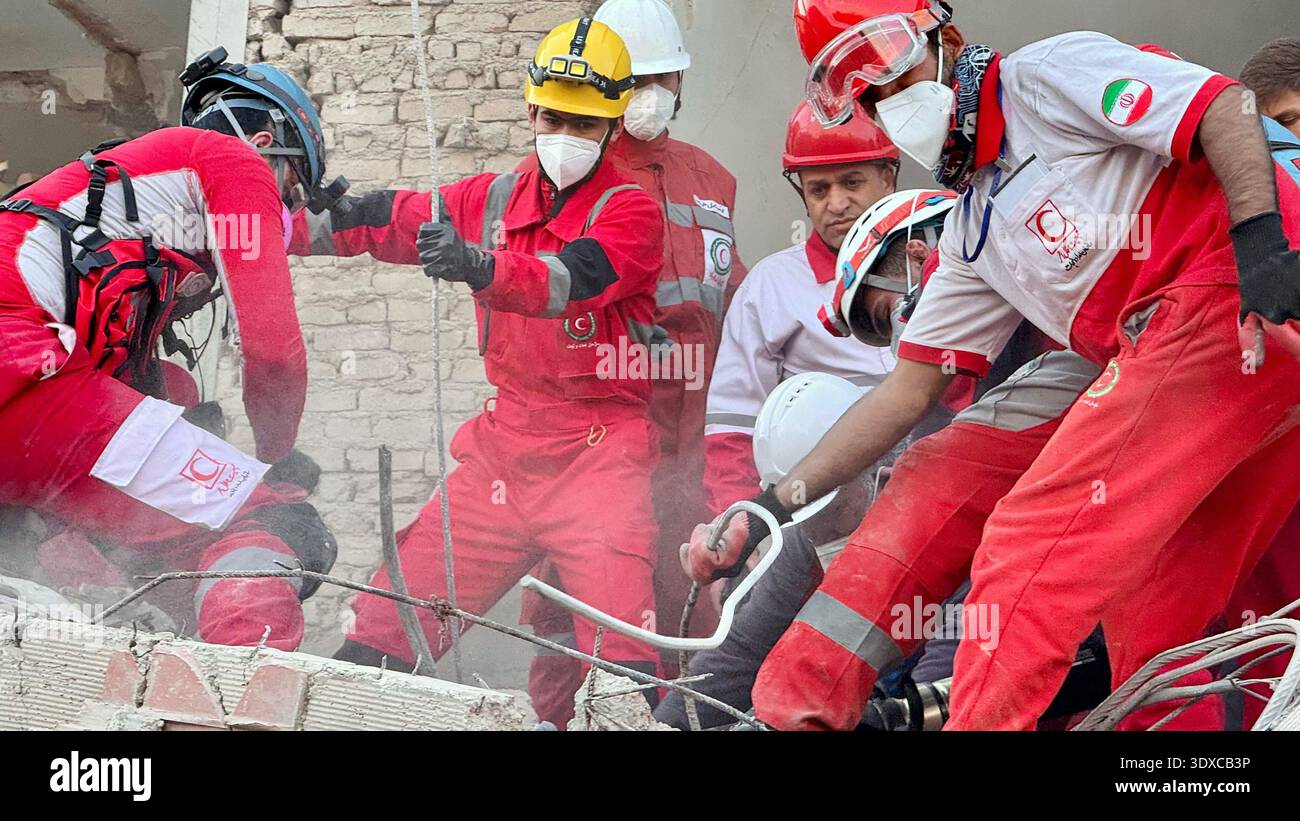 Members of Iranian rescue teams search through the rubble for victims ...