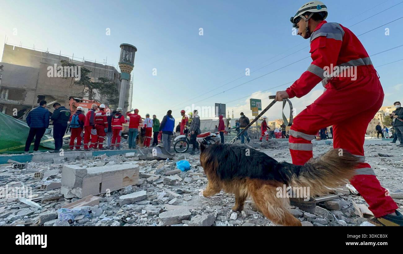 Members of Iranian rescue teams search through the rubble for victims ...