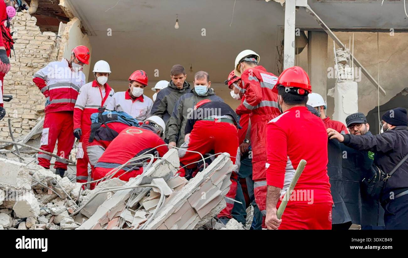 Members of Iranian rescue teams search through the rubble for victims ...