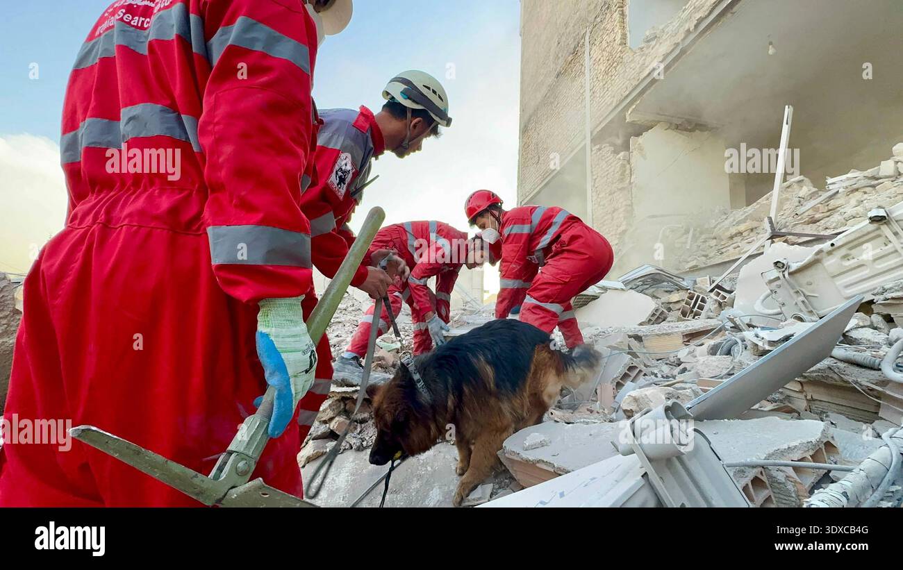 Members of Iranian rescue teams search through the rubble for victims ...