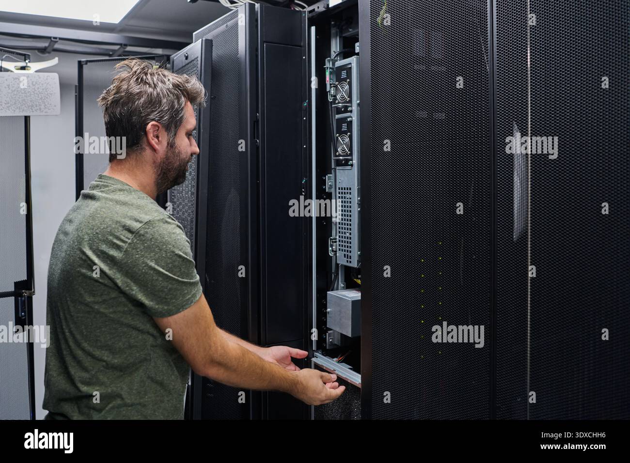 IT technician performing server maintenance in a data center rack during routine equipment inspection Stock Photo