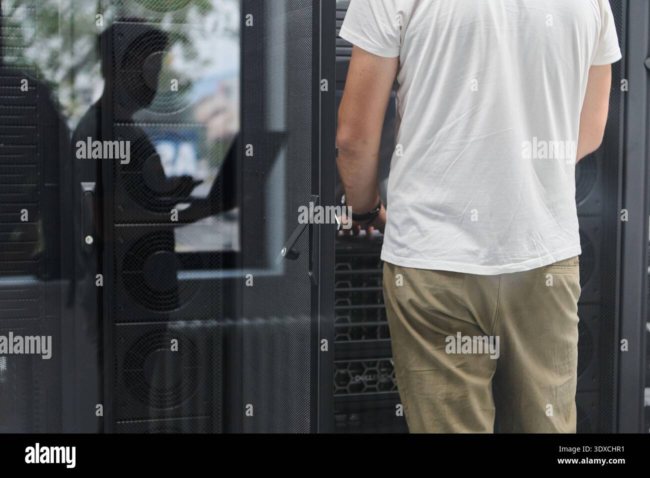 IT technician working on server rack in data center performing hardware maintenance and inspection Stock Photo