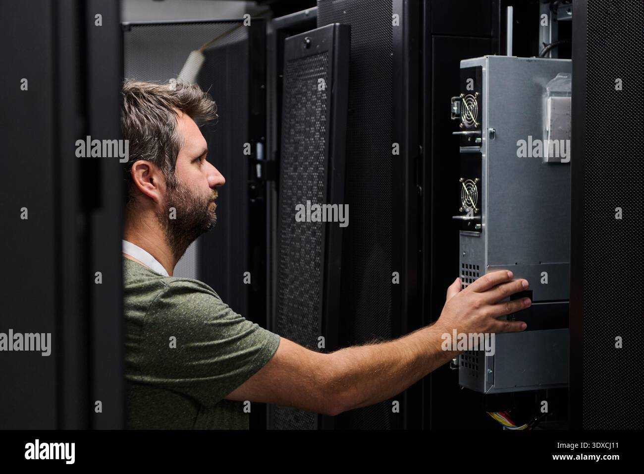 It technician installing and inspecting server hardware in a data center server rack during maintenance Stock Photo