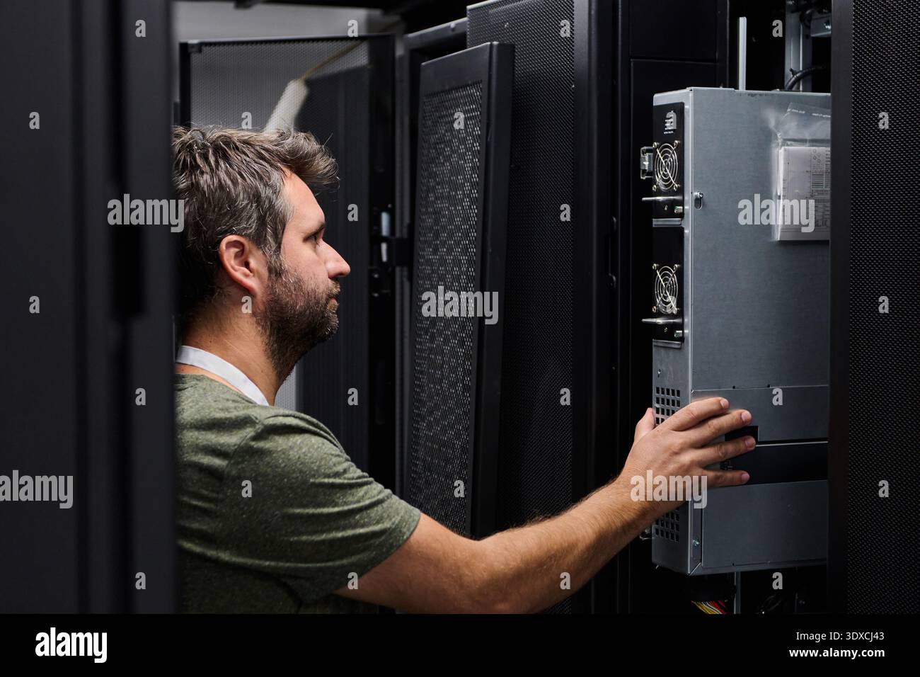 Data center technician performing server maintenance in a rack-filled server room Stock Photo