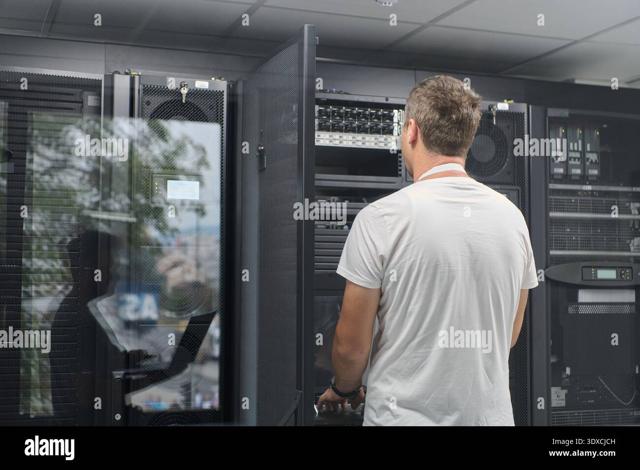 IT technician working on server rack in a modern data center checking network hardware and equipment Stock Photo