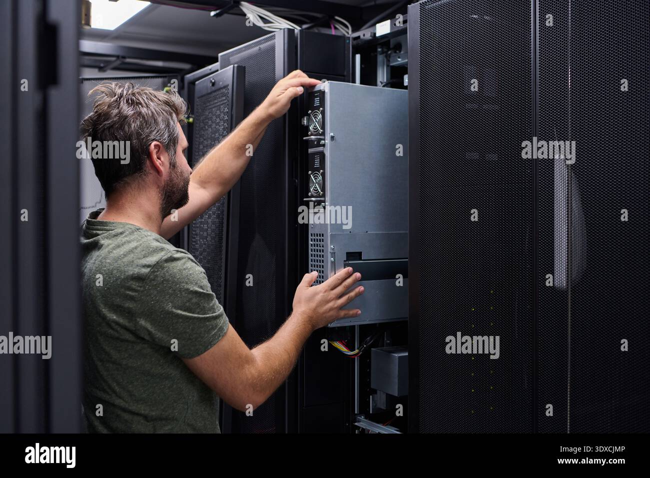 IT technician installing and maintaining servers in a data center rack for network infrastructure Stock Photo