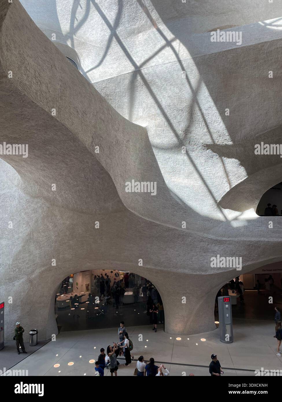 Visitors inside the Gilder Center at the American Museum of Natural History in New York City, featuring sculptural, cave-like architecture and dramati - Smartphone Captured Stock Image