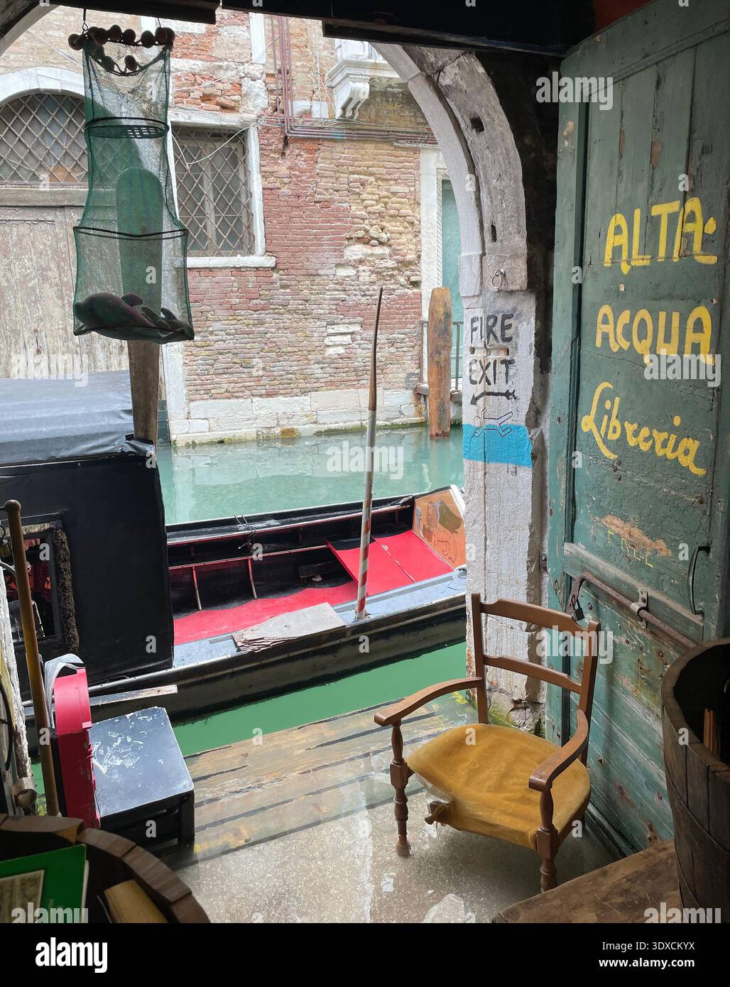 Venice, Italy - March 2 2026: Interior of a small canal-side bookstore in Venice with “alta acqua” flood warning painted on the door and a gondola moo - Smartphone Captured Stock Image